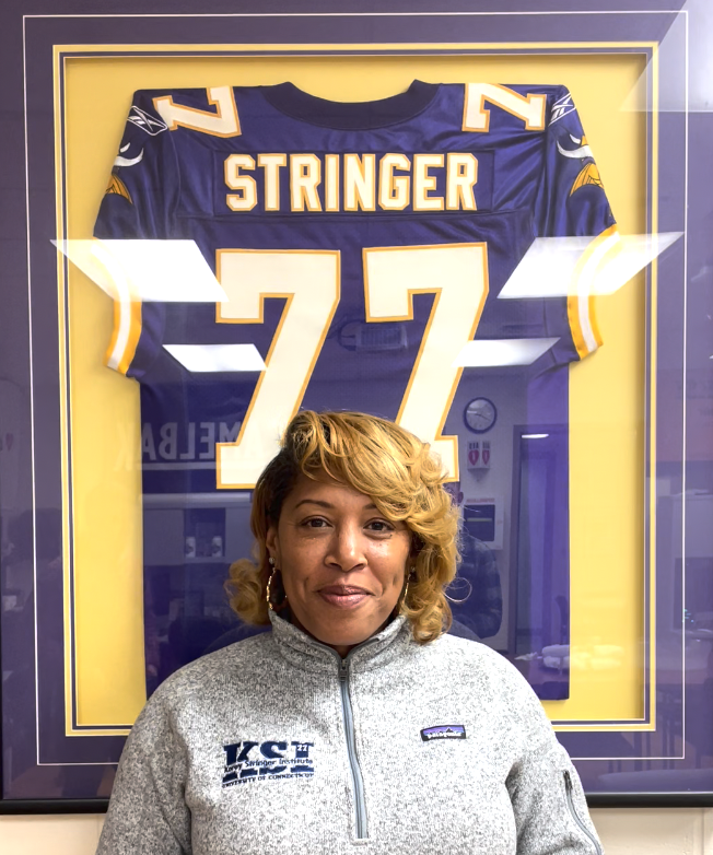 Kelci Stringer posing in front of Korey Stringer's framed jersey